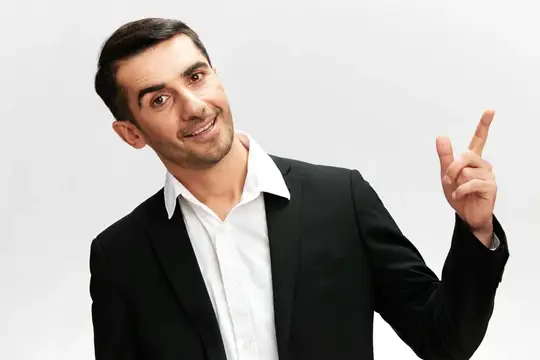 Улыбающийся мужчина в костюме поднимает указательный палец