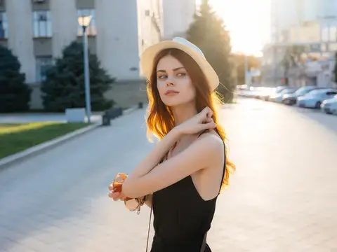 Молодая женщина в белой шляпе на залитой солнцем улице