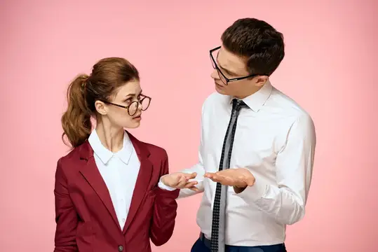 Мужчина в очках объясняет что-то коллеге на розовом фоне