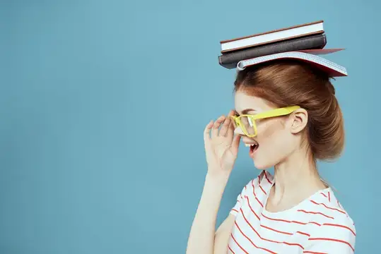 Рыжеволосая девушка в жёлтых очках с книгами на голове