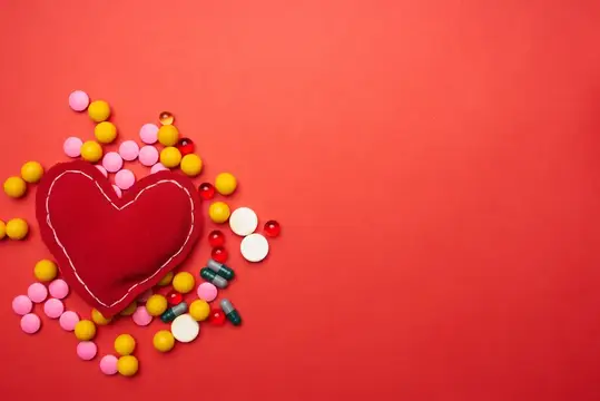 Разноцветные таблетки, мягкое сердце на красном фоне, лечение здоровья