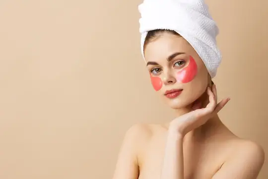 Молодая женщина с полотенцем на голове и розовыми патчами под глазами