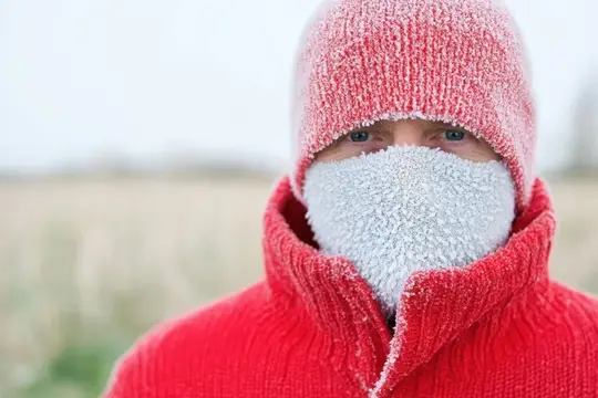 Мужчина в заснеженной красной шапке и шарфе зимой