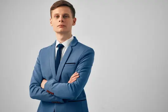 Молодой мужчина в синем костюме со скрещёнными руками