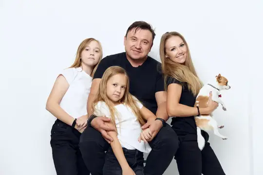 Семья с двумя дочерьми и маленькой собакой на белом фоне