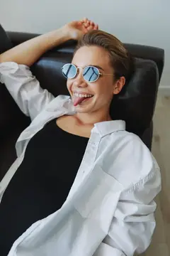Женщина лежит на диване в очках и извивается