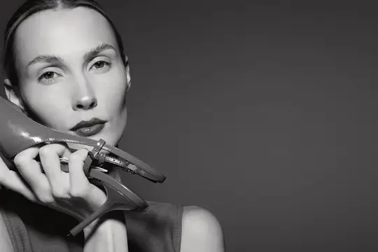 Черно-белый портрет женщины с лаковой туфлей на руке