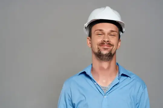 Улыбающийся мужчина в белой каске на сером фоне