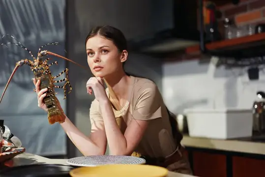 Молодая женщина с живым лобстером в руках на кухне