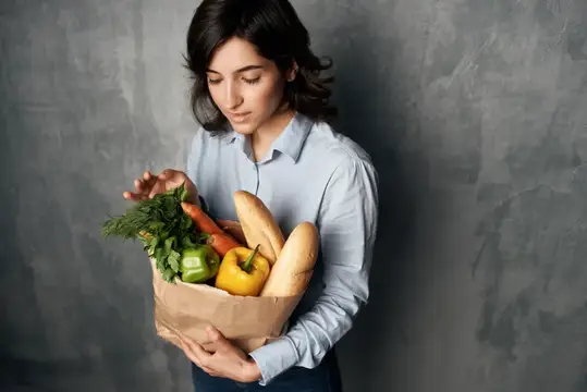 Женщина с пакетом продуктов, овощей, здоровой едой в супермаркете на тёмном фоне
