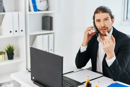 Мужчина в костюме говорит по телефону за рабочим столом в офисе
