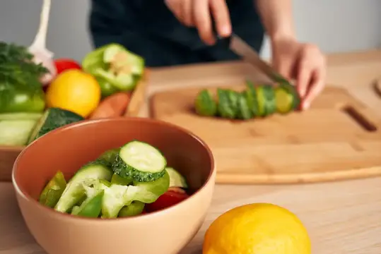 Руки нарезают свежие овощи для салата на кухне
