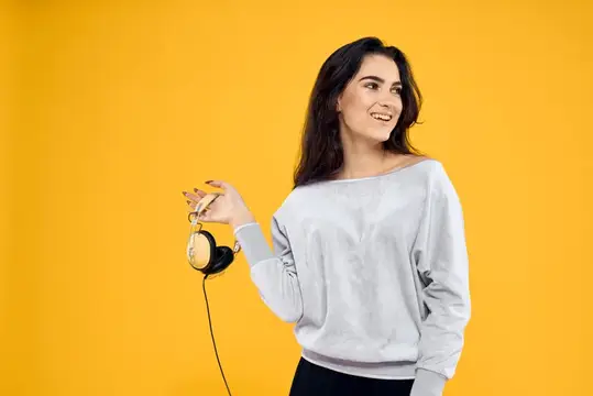 Улыбающаяся брюнетка с наушниками на желтом фоне
