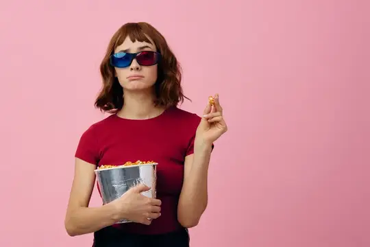 Девушка в 3D-очках с попкорном на розовом фоне