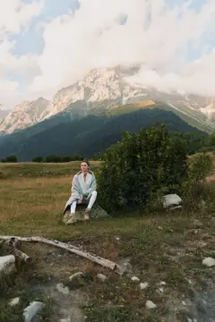 Молодая женщина отдыхает на лугу на фоне заснеженных гор