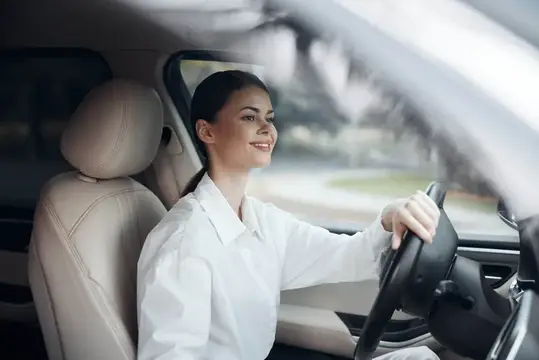 Улыбающаяся темноволосая женщина за рулём автомобиля