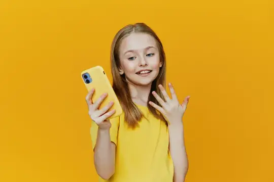 Светловолосая девочка с жёлтым смартфоном на жёлтом фоне