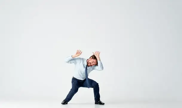 Мужчина в костюме с эмоциями прыгает в офисе на светлом фоне