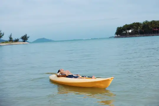 Мужчина лежит в жёлтой лодке на спокойной воде