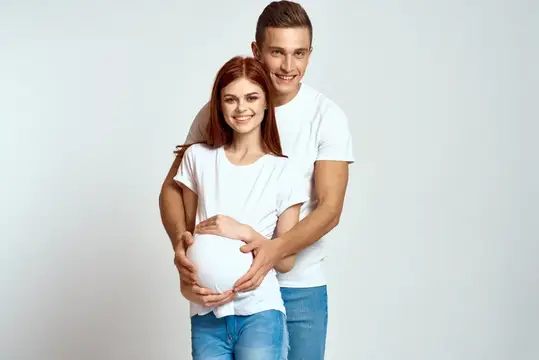Беременная женщина и молодой мужчина ждут ребенка на светлом фоне
