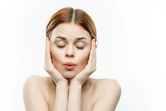 Молодая женщина с закрытыми глазами держит руки у лица на белом фоне