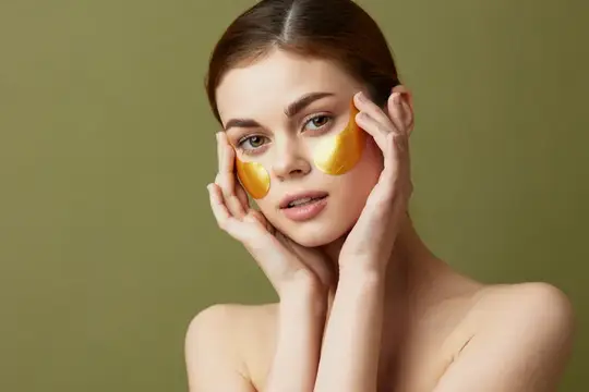 Молодая женщина с золотыми патчами под глазами на оливковом фоне
