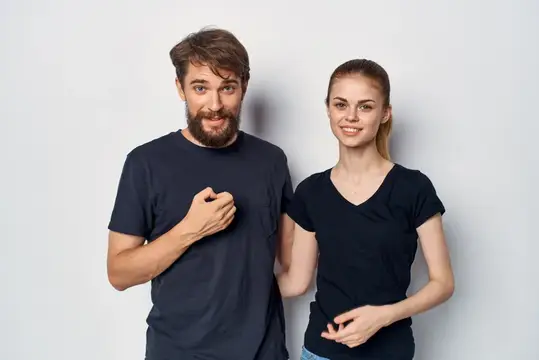 Бородатый мужчина и улыбчивая девушка в чёрных футболках на сером фоне