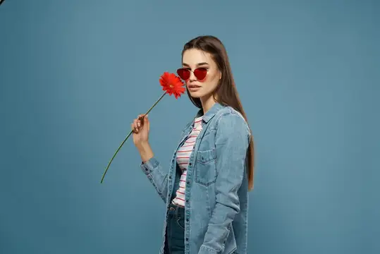 Молодая женщина в красных очках с цветком на синем фоне