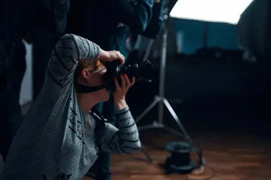 Фотограф с камерой снимает в тёмной студии