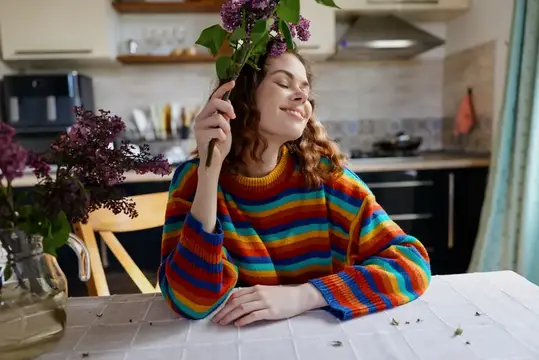 Рыжеволосая девушка в полосатой кофте с сиренью на кухне