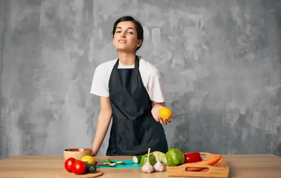 Молодая женщина в фартуке с лимоном на кухне