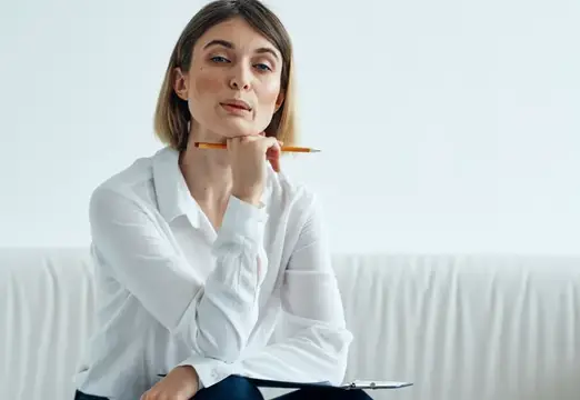 Задумчивая женщина с карандашом у лица на светлом фоне