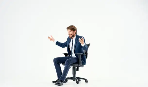Эмоциональный бизнесмен в офисном кресле работает на светлом фоне