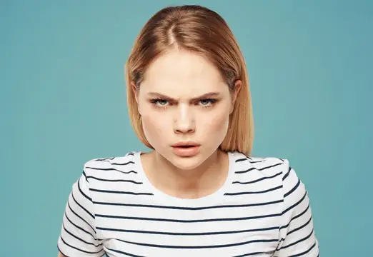 Светловолосая девушка с недовольным взглядом на голубом фоне