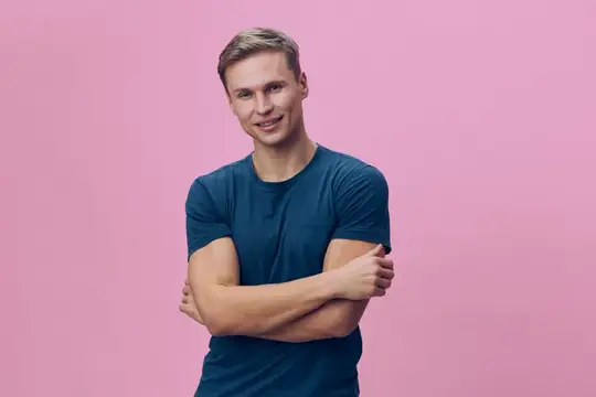 Улыбающийся светловолосый парень в синей футболке на розовом фоне
