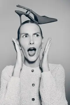 Удивлённая женщина с туфлей на голове в студии