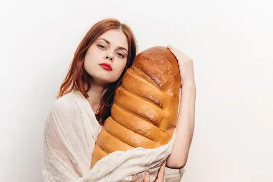 Женщина с ярким макияжем, обнимающая большую буханку хлеба