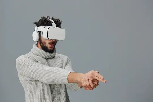 Кудрявый бородатый мужчина в VR-очках тянет руки вперёд