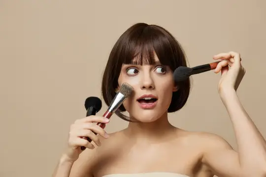 Портрет женщины, которая позирует с кисточкой для косметики, привлекательный взгляд; крупный план