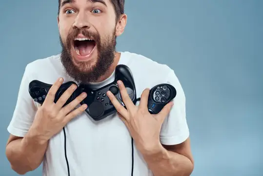 Бородатый мужчина в восторге сжимает два игровых контроллера