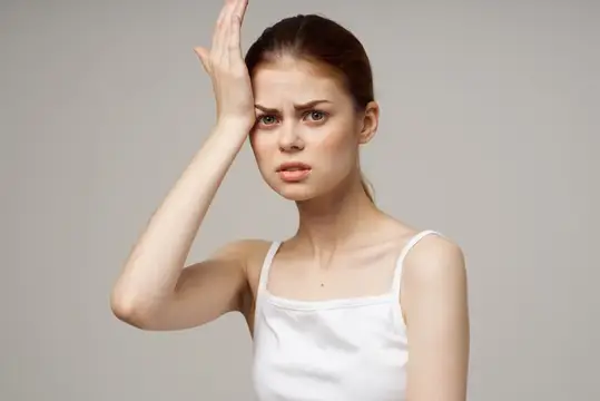 Молодая женщина с недовольным лицом приложила ладонь ко лбу