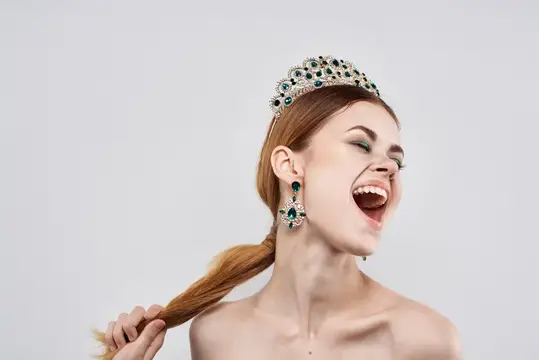 Красивая женщина с обнажёнными плечами, в украшениях и с косметикой, привлекательно смотрится на изолированном фоне