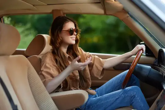 Улыбающаяся девушка в солнцезащитных очках за рулём автомобиля