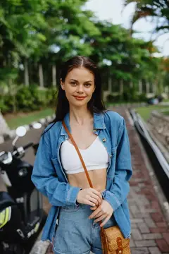 Улыбающаяся темноволосая девушка в джинсовой рубашке на улице