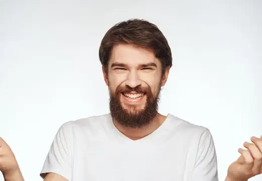 Грустный мужчина в белой футболке, эмоции, позирование на светлом фоне