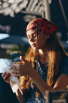 Девушка в красной бандане смотрит на экран смартфона на улице