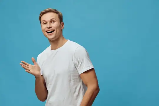 Улыбающийся парень в белой футболке жестом приветствует на синем фоне