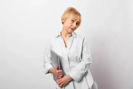 Пожилая женщина в помещении держит книгу