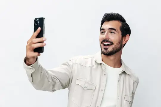 Улыбающийся бородатый мужчина делает селфи на смартфон