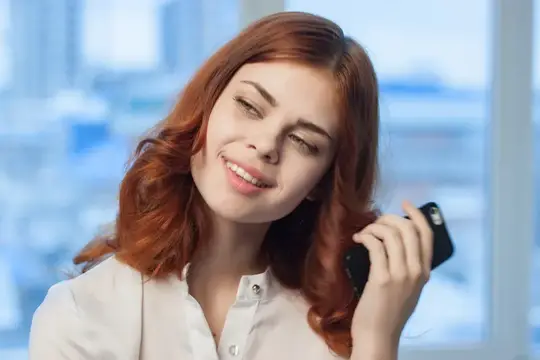 Рыжеволосая женщина в рубашке с телефоном в руках, офис, технологии, официальный стиль